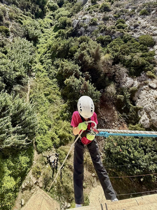 Girl on an abseiling activity above a valley